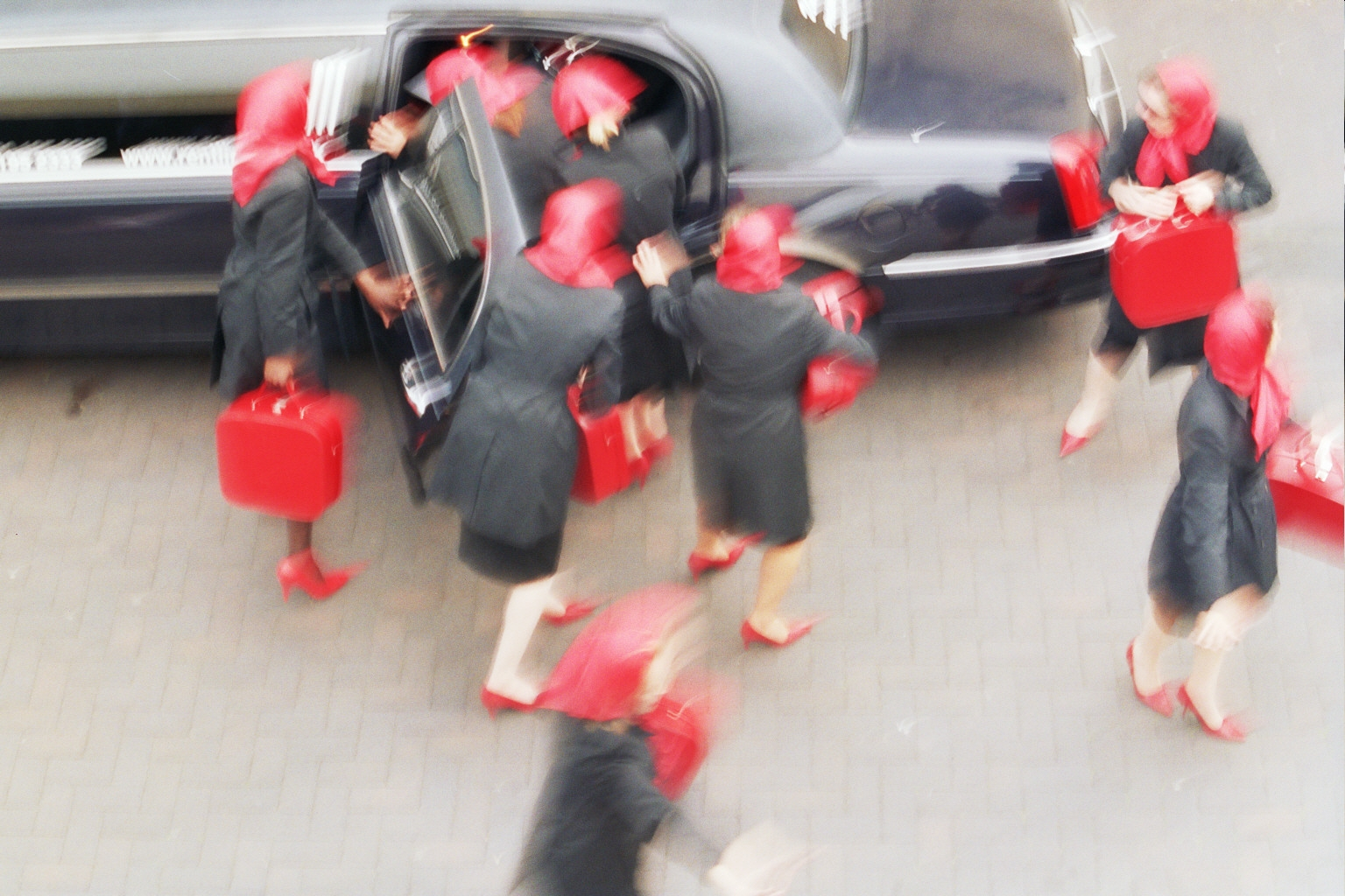 An image of identically dressed ladies getting out of a taxi. The picture is blurred.