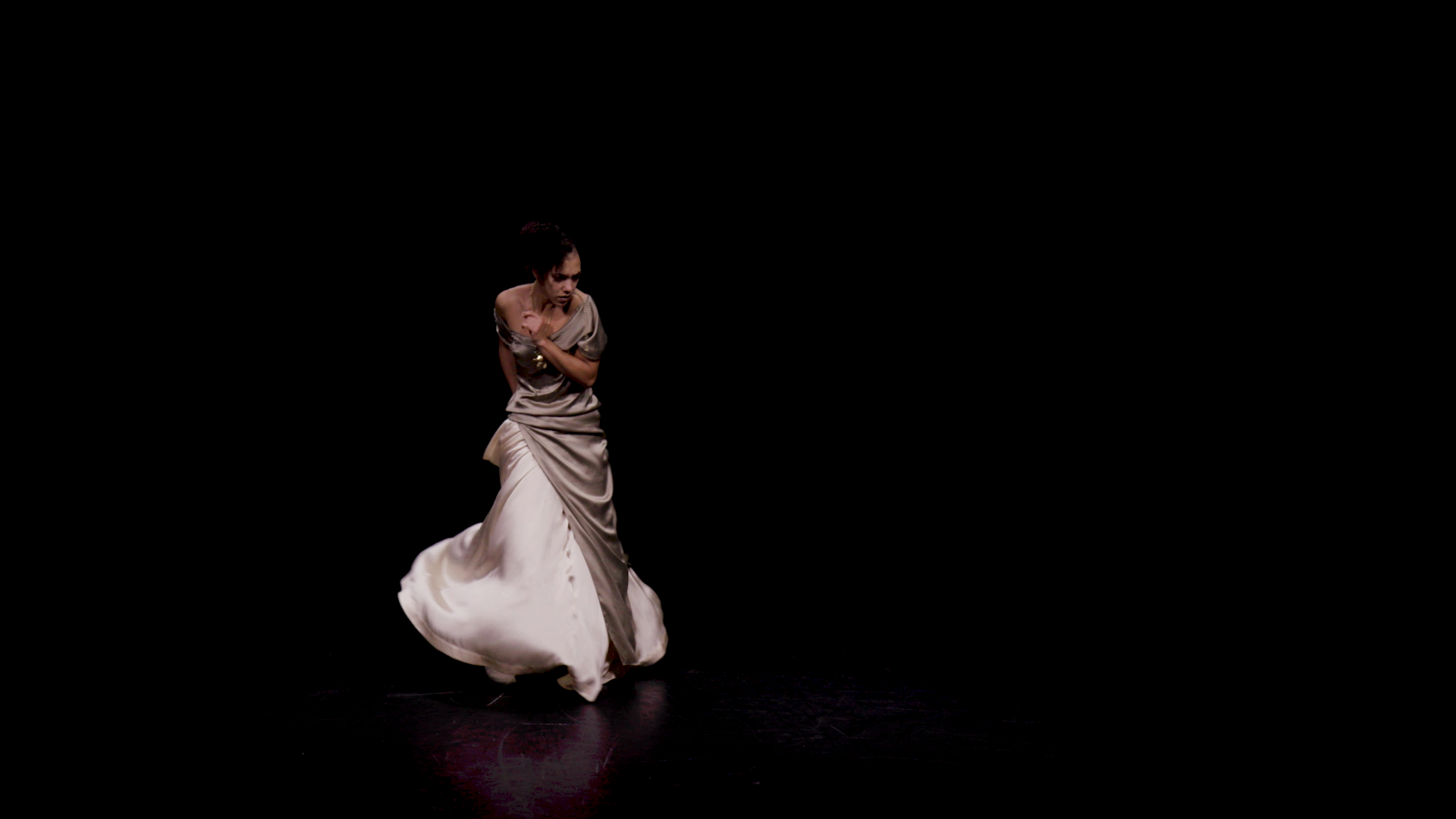 Maeva Berthelot dancing in a mink ball gown dress against a black background.