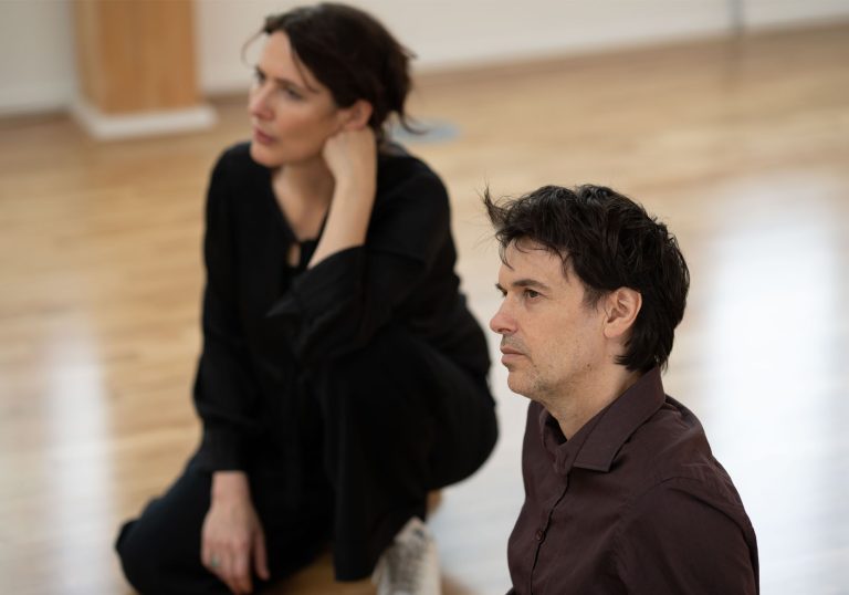 Co-Artistic Directors of Clod Ensemble Paul Clark and Suzy Willson looking across Clod Ensemble's Skylight Studio. Paul Clark is in focus and Suzy Willson is blurred into the background.