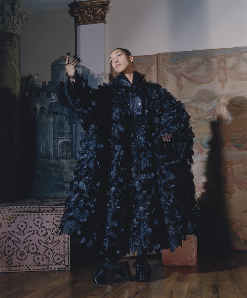 Dancer Maëva Berthelot poses in a large dark blue coat.